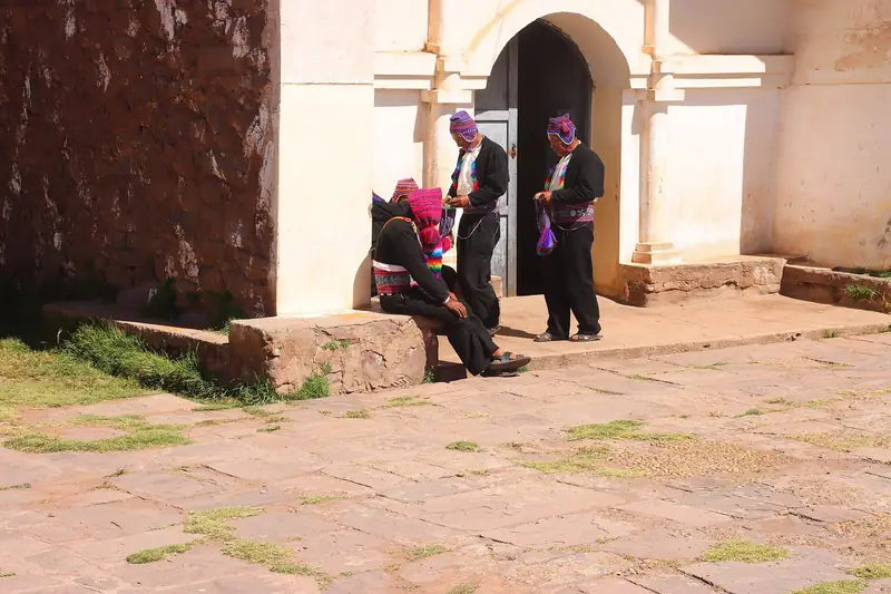 Pobladores con trajes tradicionales junto a un arco de piedra en la Isla Taquile